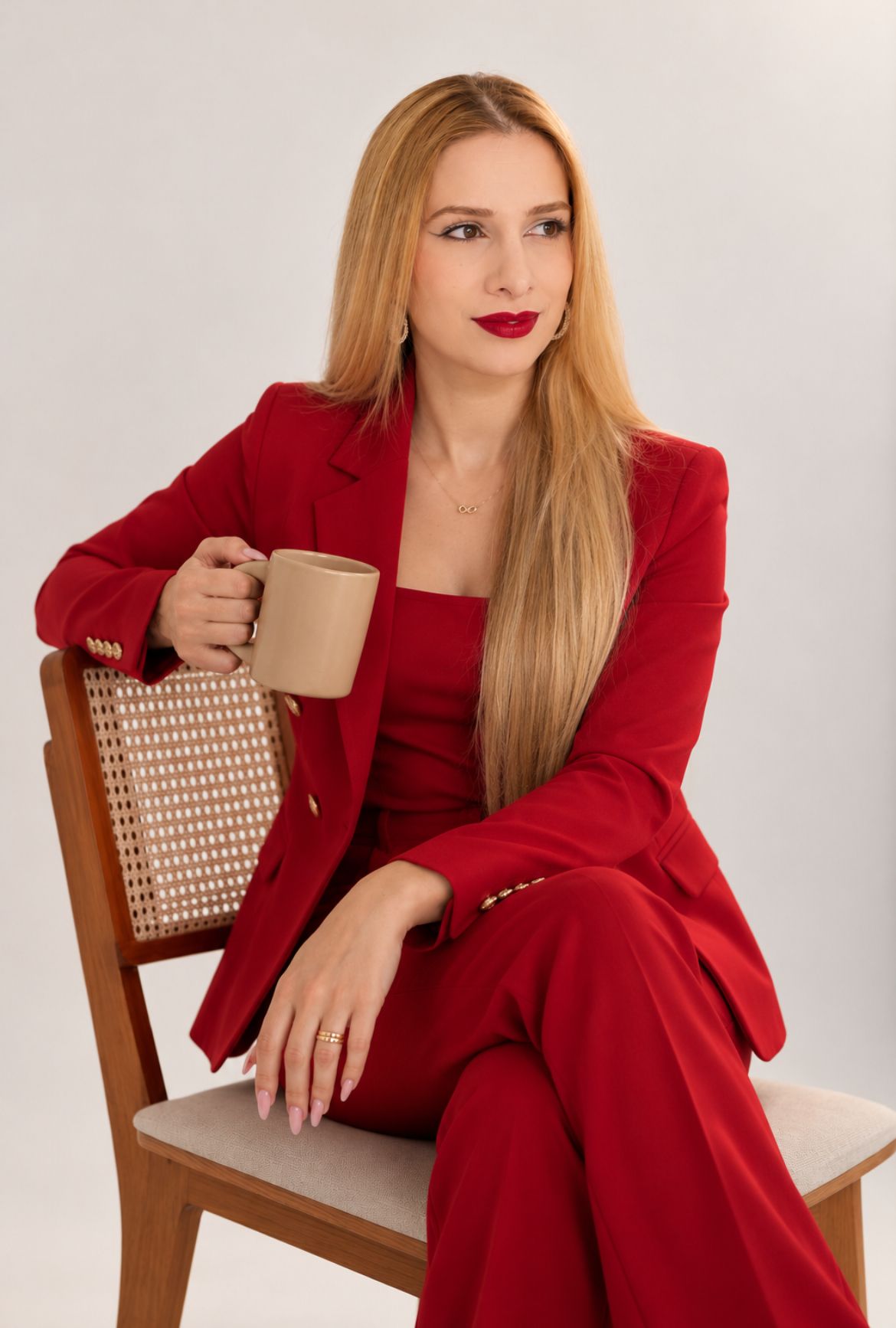 Karoline Trombim sentada em uma cadeira, com um café nas mãos